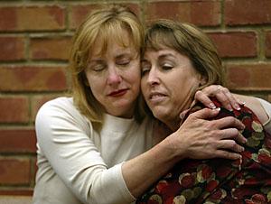 Chigiy Binell, left, and Janice Burnham hug before the start of a news conference in Los Gatos on Thursday concerning their good friend Jeanine Harms.